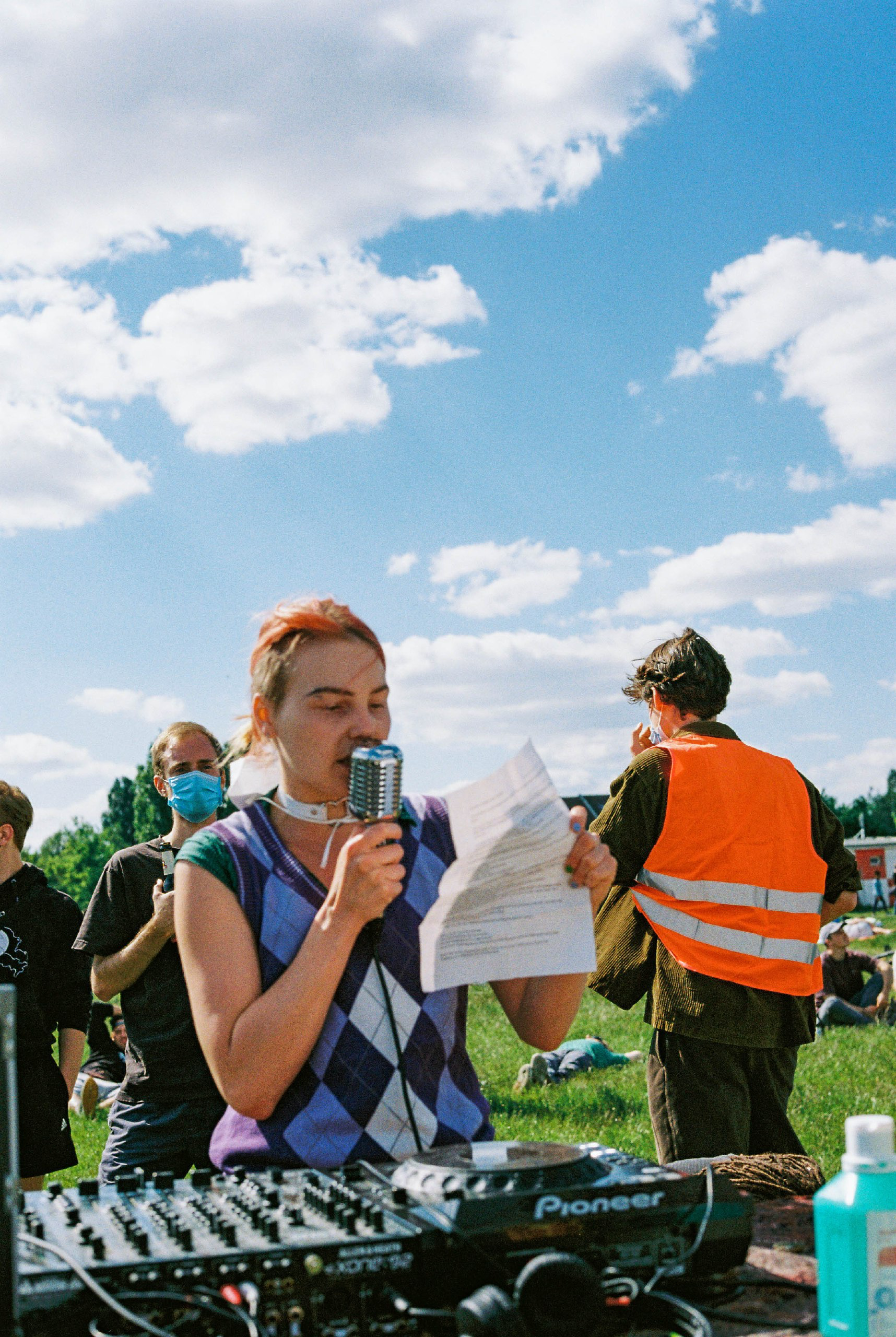Person steht mit Zettel in der Hand auf dem Tempelhofer Feld und hält Rede