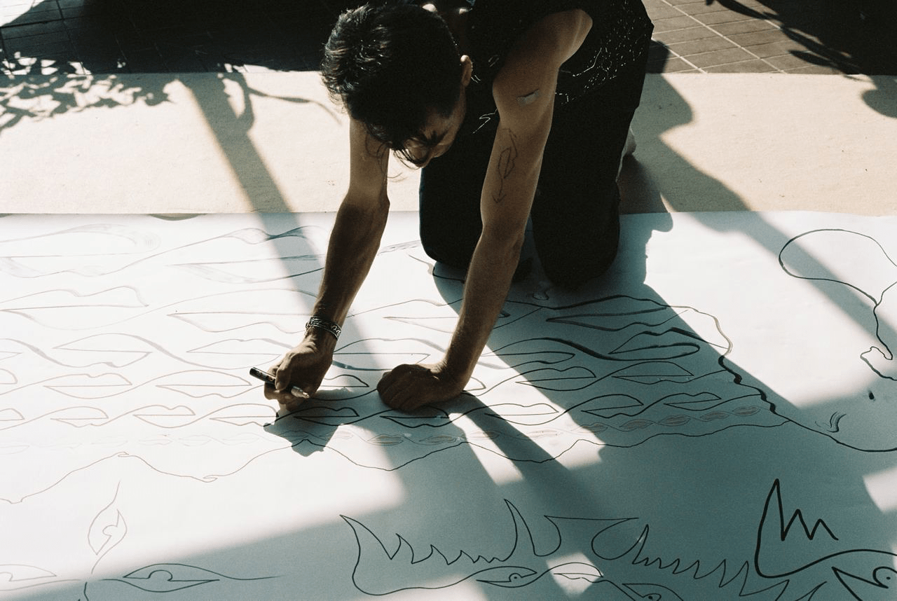 Livestream: Person kniet auf dem Boden und malt auf riesiges Papier